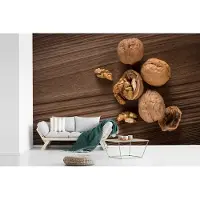 MuchoWow Fotobehang vinyl - Gekrakte walnoot op een donkerbruine tafel breedte 420 cm x hoogte 280 cm - Foto print op behang (in 7 formaten beschikbaar)